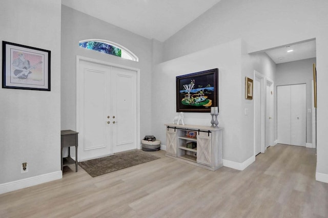 entryway featuring high vaulted ceiling and light hardwood / wood-style flooring