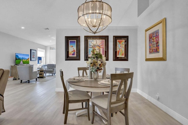 dining space with an inviting chandelier, ornamental molding, and light hardwood / wood-style flooring