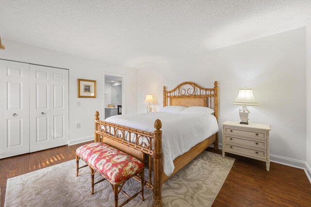 bedroom with dark hardwood / wood-style floors, ensuite bath, a closet, and a textured ceiling