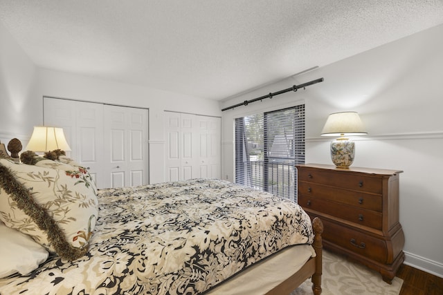 bedroom featuring multiple closets, wood-type flooring, and a textured ceiling