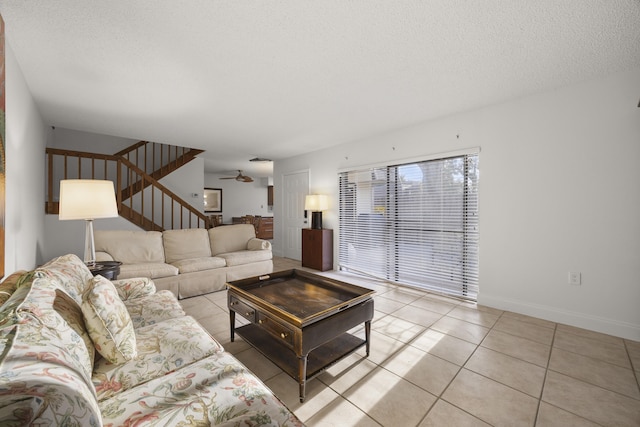 living room featuring light tile patterned flooring, ceiling fan, and a textured ceiling