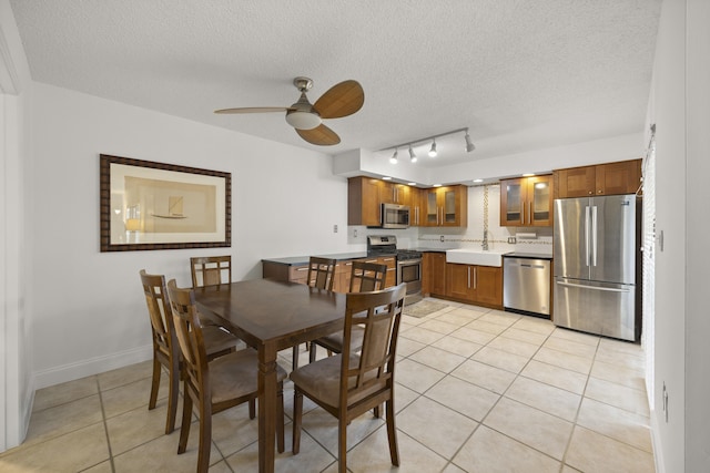 dining area with rail lighting, sink, light tile patterned floors, ceiling fan, and a textured ceiling