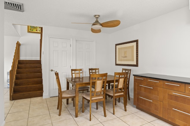 tiled dining room featuring a textured ceiling and ceiling fan