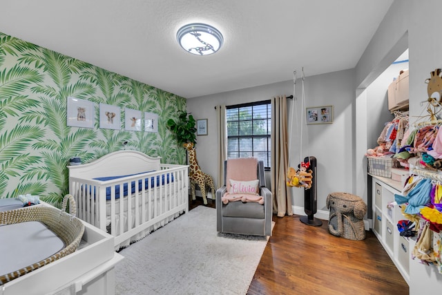 bedroom featuring dark hardwood / wood-style floors and a nursery area