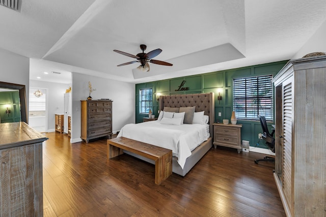 bedroom featuring dark wood-type flooring, connected bathroom, ceiling fan, and a raised ceiling