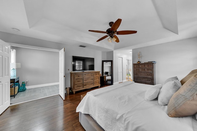 bedroom featuring ceiling fan, a raised ceiling, and dark hardwood / wood-style floors