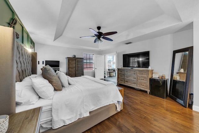 bedroom featuring ceiling fan, a tray ceiling, and dark hardwood / wood-style flooring