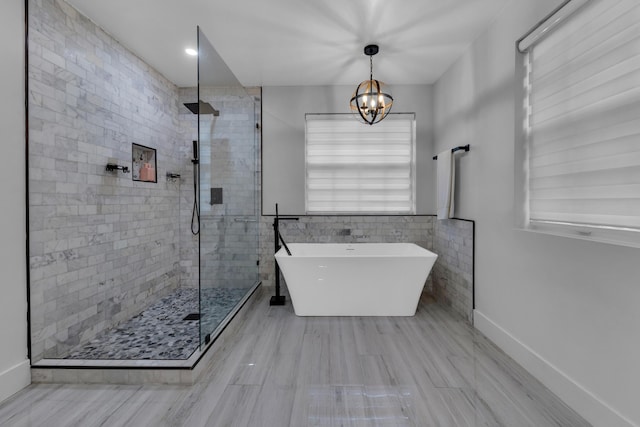 bathroom featuring an inviting chandelier and shower with separate bathtub