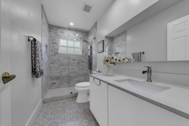 bathroom with vanity, toilet, tiled shower, and tile patterned floors