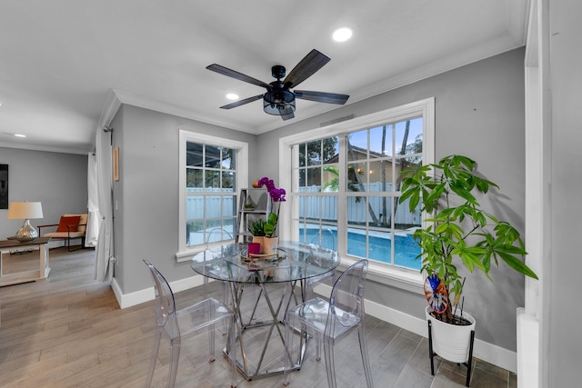 dining room with light wood-type flooring, crown molding, and a healthy amount of sunlight