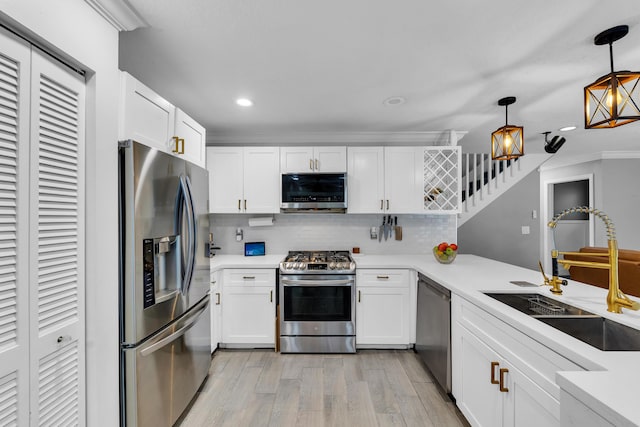 kitchen featuring white cabinetry, hanging light fixtures, sink, backsplash, and stainless steel appliances