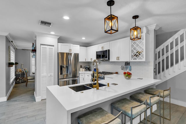 kitchen with kitchen peninsula, hanging light fixtures, decorative backsplash, a breakfast bar area, and stainless steel appliances