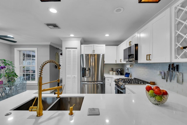 kitchen featuring sink, stainless steel appliances, white cabinetry, and decorative backsplash