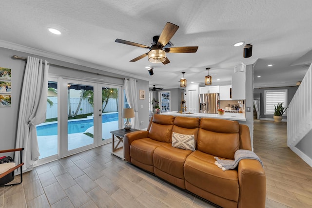 living room featuring ceiling fan, ornamental molding, french doors, and a healthy amount of sunlight