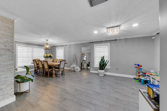 dining space featuring light hardwood / wood-style flooring, an inviting chandelier, crown molding, and a textured ceiling