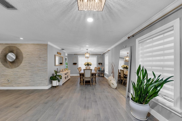 dining space with a textured ceiling, hardwood / wood-style floors, a chandelier, and ornamental molding