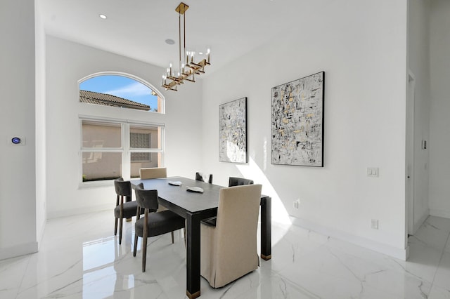 dining area with a towering ceiling and a chandelier