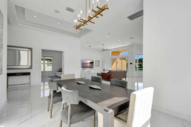 dining space featuring a tray ceiling, ceiling fan with notable chandelier, and plenty of natural light