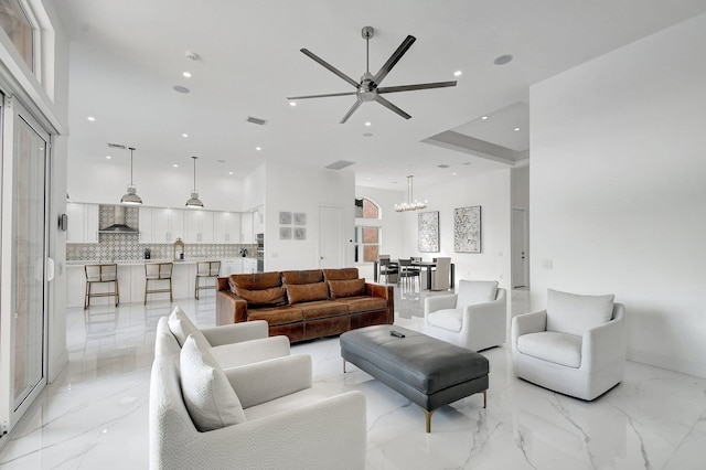 living room with ceiling fan with notable chandelier and a high ceiling