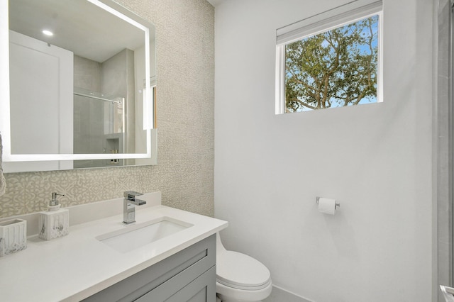 bathroom with vanity, backsplash, a shower with shower door, and toilet