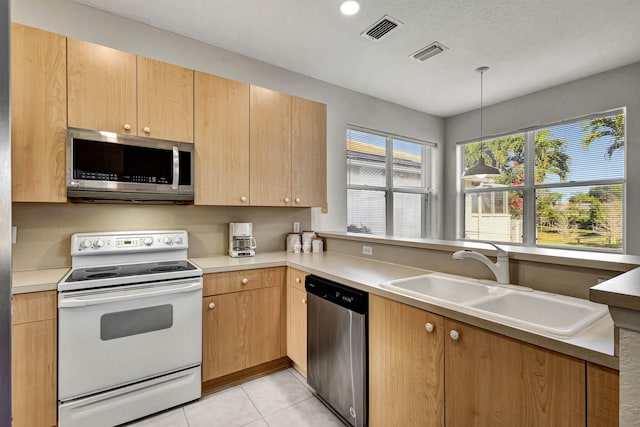 kitchen featuring stainless steel appliances, light tile patterned flooring, sink, and decorative light fixtures