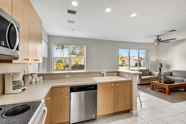 kitchen with sink, a textured ceiling, appliances with stainless steel finishes, kitchen peninsula, and pendant lighting