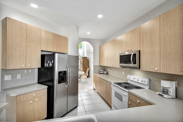 kitchen featuring light brown cabinetry, light tile patterned flooring, and appliances with stainless steel finishes