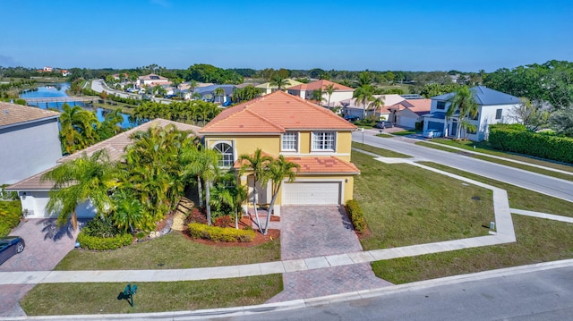 view of front of home with a garage, a front lawn, and a water view