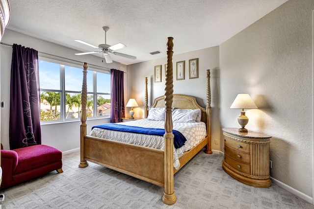 bedroom featuring ceiling fan, light colored carpet, and a textured ceiling