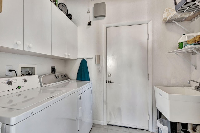 clothes washing area with light tile patterned flooring, cabinets, sink, and washing machine and dryer