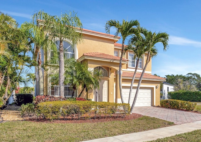 mediterranean / spanish house with a garage and a front lawn