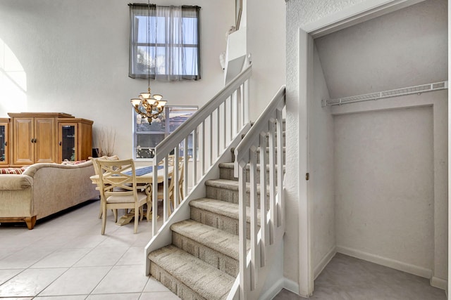 stairs featuring tile patterned flooring, a high ceiling, and a notable chandelier