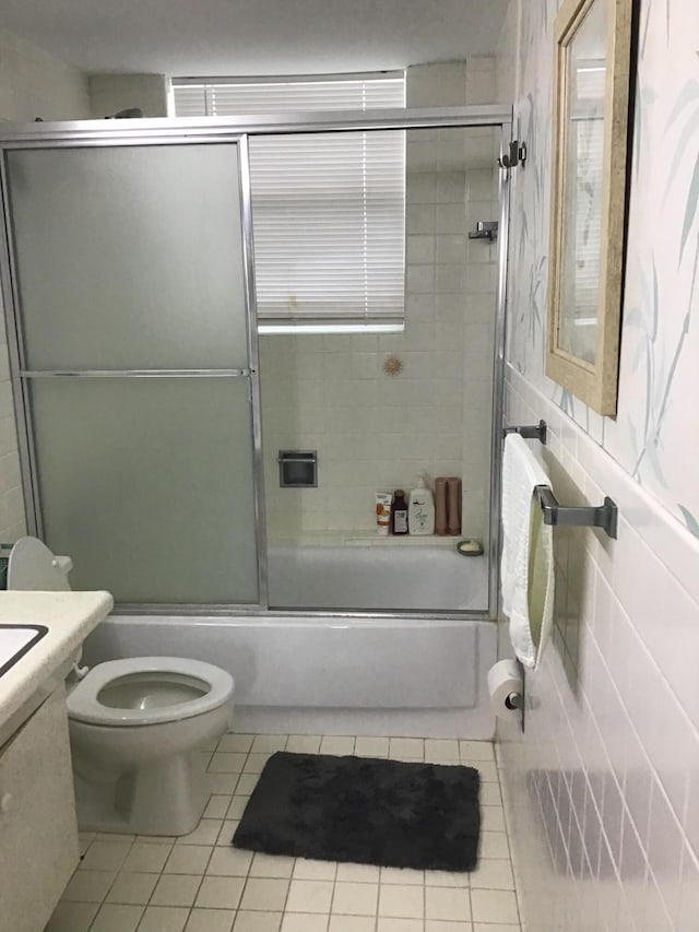 full bathroom with combined bath / shower with glass door, vanity, toilet, and tile patterned flooring