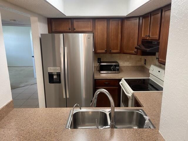 kitchen with sink, stainless steel refrigerator with ice dispenser, tile patterned floors, and white range with electric stovetop