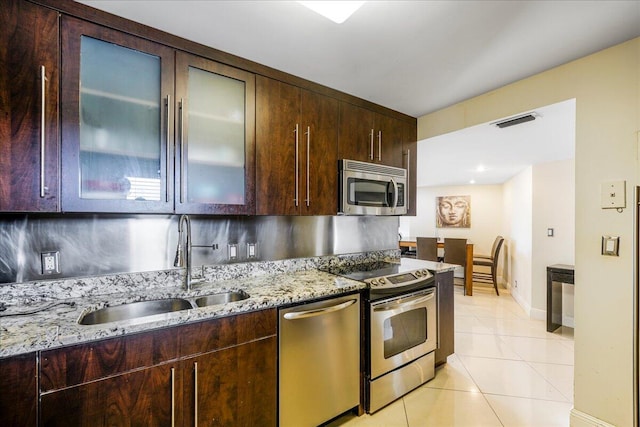 kitchen featuring backsplash, sink, stainless steel appliances, light tile patterned floors, and light stone counters