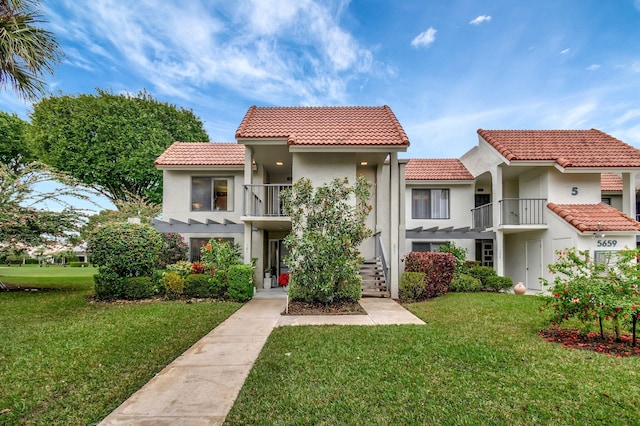 mediterranean / spanish home featuring a balcony and a front lawn