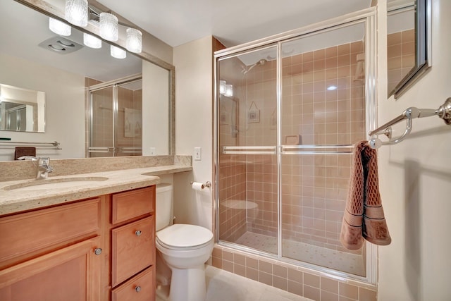 bathroom featuring tile patterned flooring, vanity, an enclosed shower, and toilet