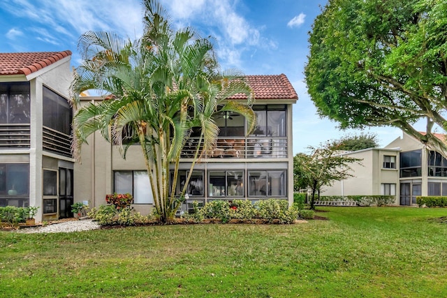 rear view of house featuring a sunroom and a yard