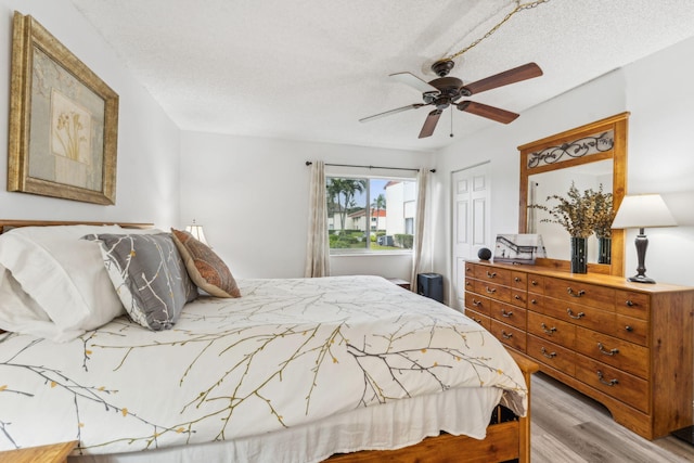 bedroom with a closet, a textured ceiling, ceiling fan, and light hardwood / wood-style floors