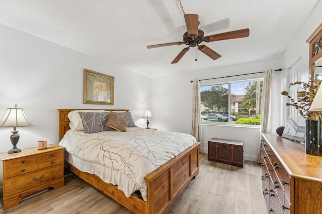 bedroom featuring ceiling fan, light hardwood / wood-style flooring, and a textured ceiling