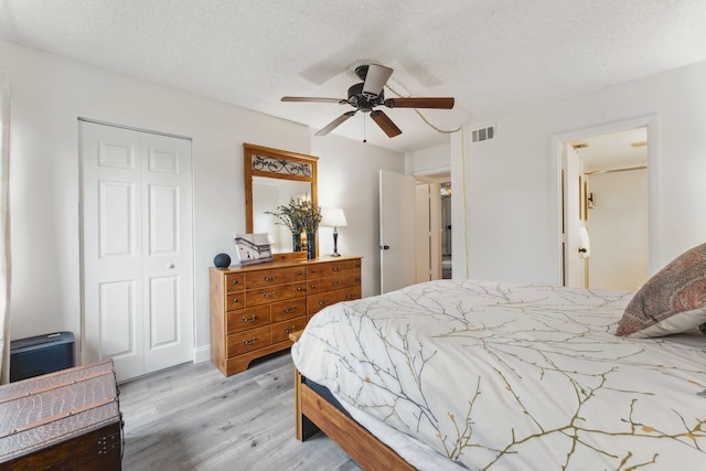 bedroom with a textured ceiling, ceiling fan, and light hardwood / wood-style floors