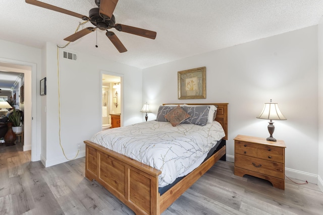 bedroom with ensuite bathroom, a textured ceiling, ceiling fan, and light hardwood / wood-style floors