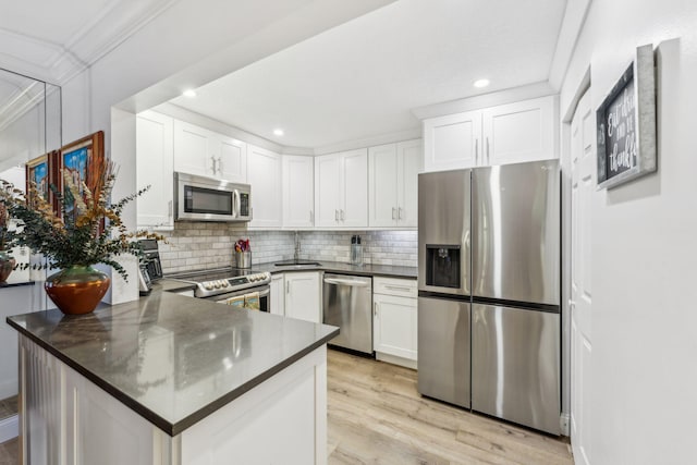 kitchen featuring appliances with stainless steel finishes, white cabinetry, sink, kitchen peninsula, and light wood-type flooring