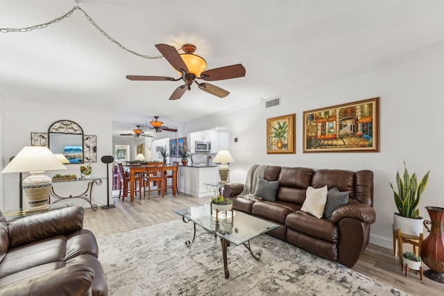 living room featuring ceiling fan, ornamental molding, and light wood-type flooring