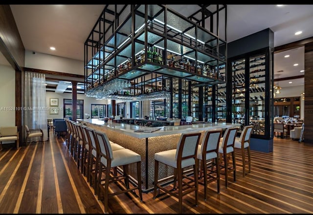 bar with a towering ceiling and dark hardwood / wood-style floors