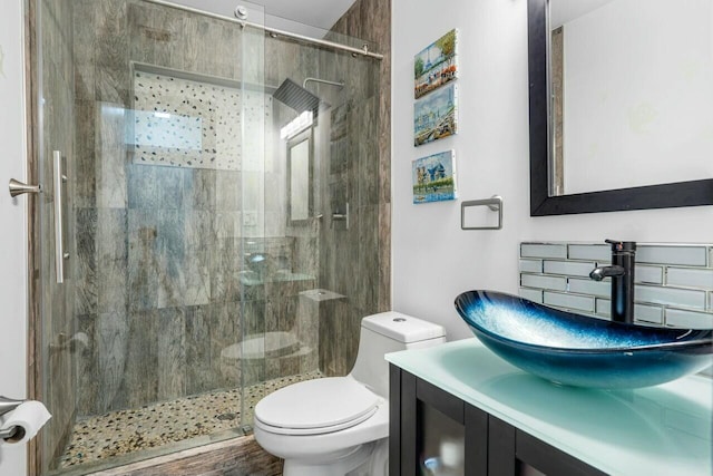 bathroom featuring vanity, toilet, and a tile shower