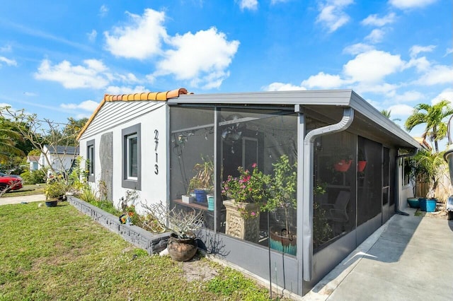 view of home's exterior with a sunroom and a yard