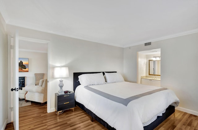 bedroom with connected bathroom, ornamental molding, and light wood-type flooring