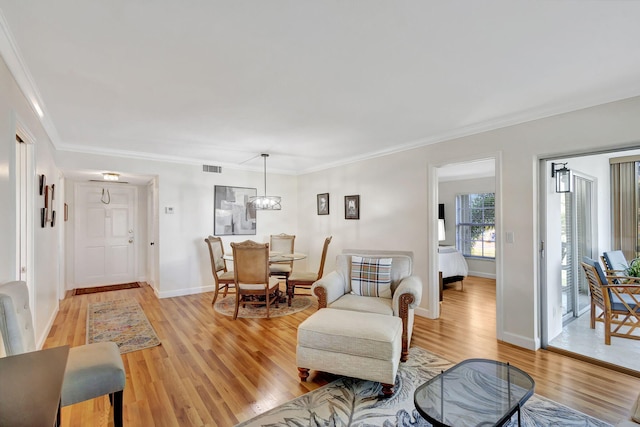 living room with light wood-type flooring, an inviting chandelier, and ornamental molding