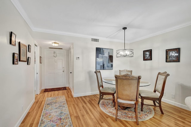 dining room with crown molding, an inviting chandelier, and light hardwood / wood-style floors